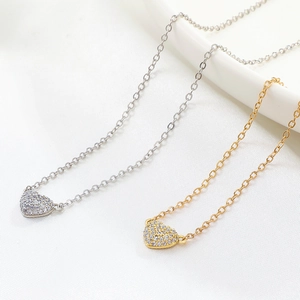Detailed view of silver and gold heart pendants with pave-set shimmering zircon stones