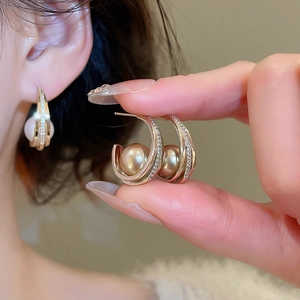 Detailed macro of C-shaped rose gold earrings with pavé zircons and champagne pearls