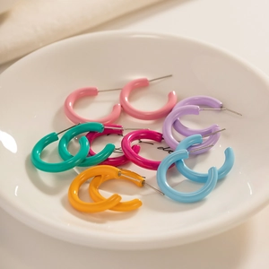 Colorful resin C-shape hoop earrings set in six vibrant shades on a white ceramic plate