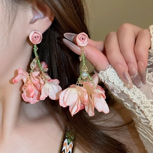 Detail of pink fabric flower earrings with green beads and long tassel design