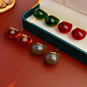 Minimalist resin drop earrings in green and amber with gold trim in a luxury display