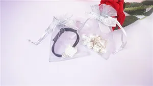 Close-up of white organza drawstring gift bags with silver bows and pearl jewelry inside