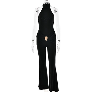 Detail of black halterneck jumpsuit featuring a golden owl buckle and slim fit flared legs