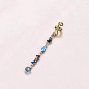 Detailed view of a gold snake-patterned ear cuff with hanging blue crystal pendants