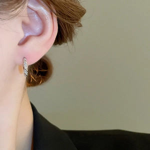 Close-up of a silver twisted texture hoop earring on ear showing elegant metallic finish