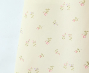 Close-up of yellow floral fabric with pink and purple blossoms on summer midi dress