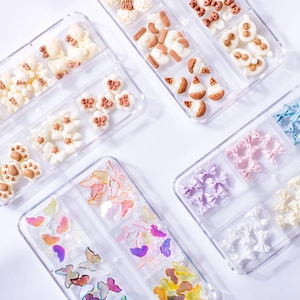 Assorted resin nail art charms featuring bears and bows in transparent storage boxes