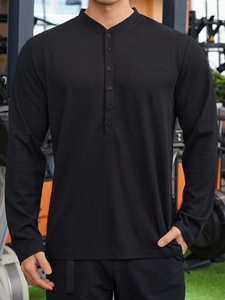 Detail shot of black waffle knit fabric and buttoned Henley neckline on men's polo shirt
