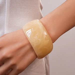 Macro detail of wide resin bangle showing translucent marble texture and amber yellow tones