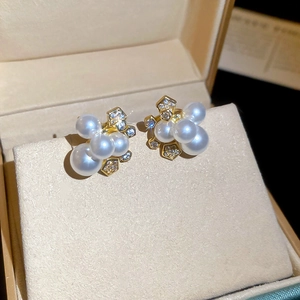 Vue détaillée des boucles d'oreilles en perles et zircons sur un présentoir à bijoux doré