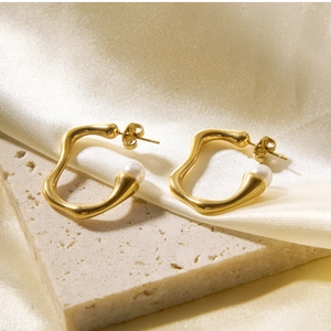 Detail of 18k gold irregular hoop earrings with white pearls on elegant silk background