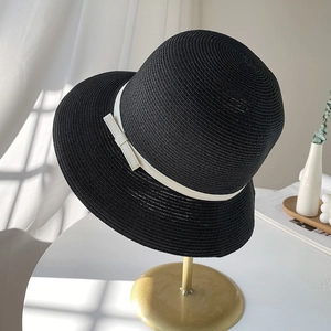 Elegant black straw sun hat with white bow ribbon on a display stand with sunlight