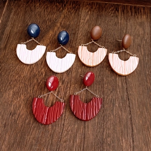 Detail view of U-shaped leather resin earrings with pleated texture in vintage colors