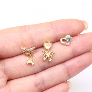 Detailed close-up of three gold spider and butterfly heart nose studs with rhinestones