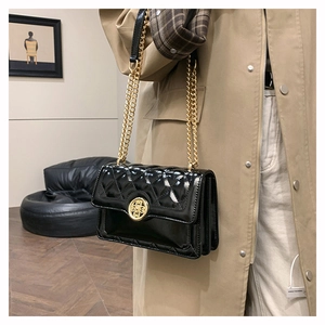 Detail of black quilted leather shoulder bag with gold chain and multi-compartment design