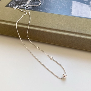 Detail of 925 sterling silver layered necklace with polished bead pendant and sleek chains