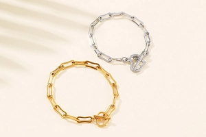 Detail of paperclip chain bracelets in gold and silver with heart-shaped toggle clasps