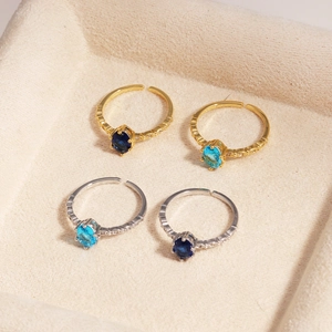 Detailed top view of four adjustable blue zircon rings in a beige velvet jewelry box