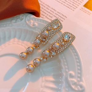 Dettaglio degli orecchini vintage in oro con perle artificiali e strass scintillanti