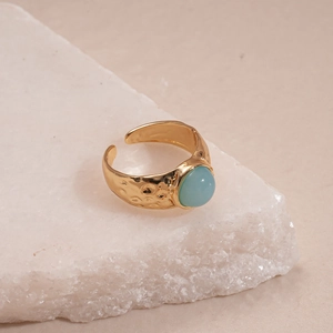 Close-up of golden hammered ring with an oval light blue cabochon resin gemstone