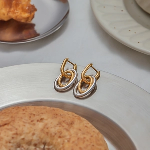 Vue détaillée de boucles d'oreilles géométriques bicolores sur un plateau métallique
