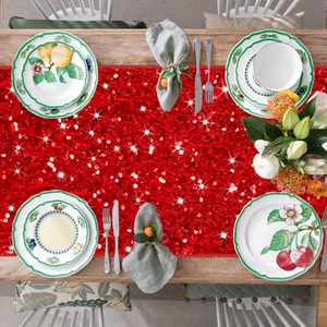 Top view of shimmering red sequin table runner on a festive wooden dining table setup