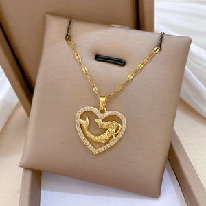 Macro shot of gold heart mermaid pendant with crystals on a jewelry box cushion