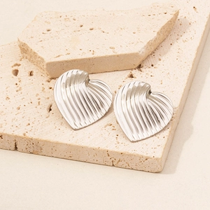 Macro detail of silver heart stud earrings with radiating pleated metal texture on stone