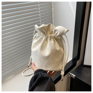 Detail of cream white bucket bag showing drawstring closure and fine marble texture