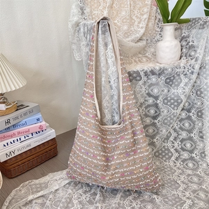 Detail of bohemian knit tote bag with colorful sequins on beige textured fabric
