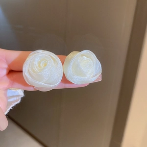 Close-up of white rose flower earrings featuring a delicate shimmering glossy finish