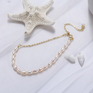 Détail de perles d'eau douce blanches et chaîne dorée avec accents d'étoile de mer et coquillage