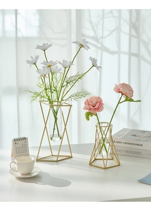 Macro shot of geometric gold metal frame flower vases with glass tubes and faux blooms