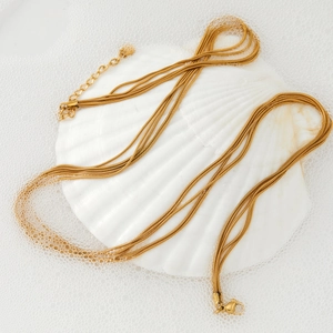 Multi-layer gold snake chain necklace displayed on a white shell with foam background