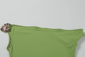 Detail of green summer dress featuring a decorative gold butterfly metal element on shoulder