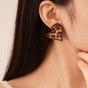 Gros plan de boucles d'oreilles cœur imprimé léopard sur modèle avec texture mate marron