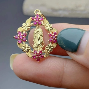 Macro shot of gold Virgin of Guadalupe pendant with pink zirconia stones and floral details
