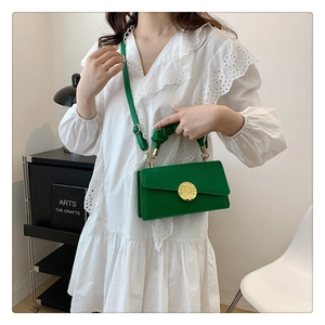 Détail du sac plissé vert avec un grand fermoir rond ondulé en métal doré