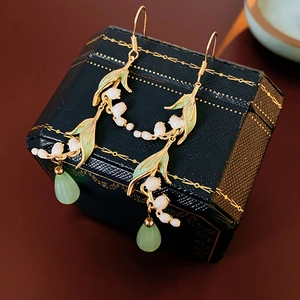 Detailed close-up of lily of the valley earrings on a luxury green velvet jewelry box