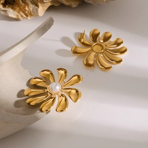 Detailed view of 18k gold sunflower earrings with pearls on textured stone background
