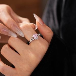 Close-up of elegant crown ring with pink zircon gemstone on model hand with black velvet