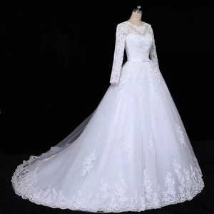 Detail of elegant bridal gown featuring long lace sleeves and a long flowing train on mannequin