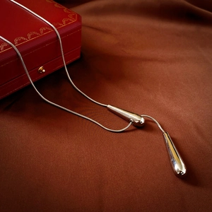 Detail view of silver snake chain with polished teardrop pendants on brown satin