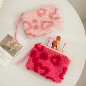Pink and rose red plush cosmetic bags with heart patterns on a white table