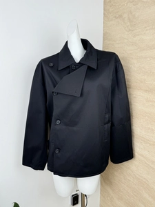 Close-up of black double-breasted jacket showing asymmetric lapel and matte fabric detail