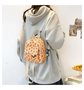 Detail of light orange corduroy mini backpack with cherry prints on a female model