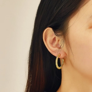 Macro shot of French retro twisted gold hoop earrings showing textured wire details