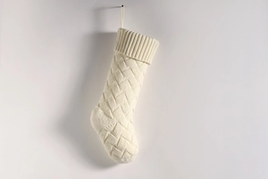 Detail view of cream white knitted Christmas stocking with textured pattern and hanging loop