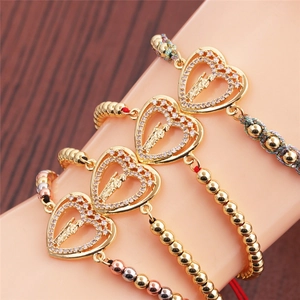 Detail of four gold-plated heart charm bracelets with zircon inlay and beaded straps