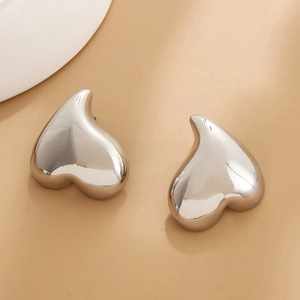 Macro shot of polished silver heart earrings showing mirror-like metallic finish